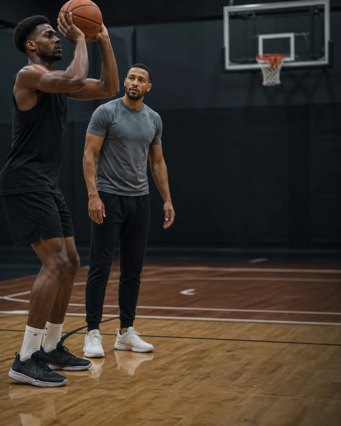 Basketball coach observing an athlete during a focused indoor shooting session
